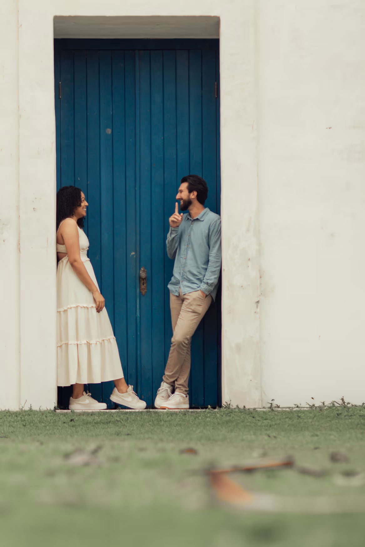 Casal encostado em uma porta azul