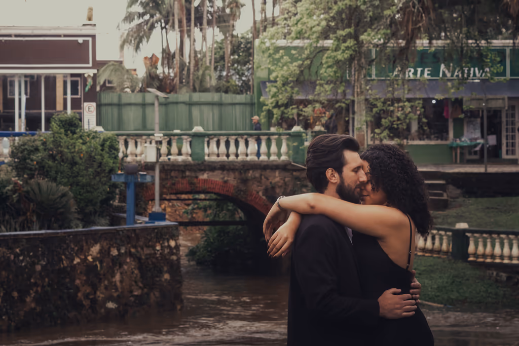 Casal abraçado em uma praça com ponte ao fundo