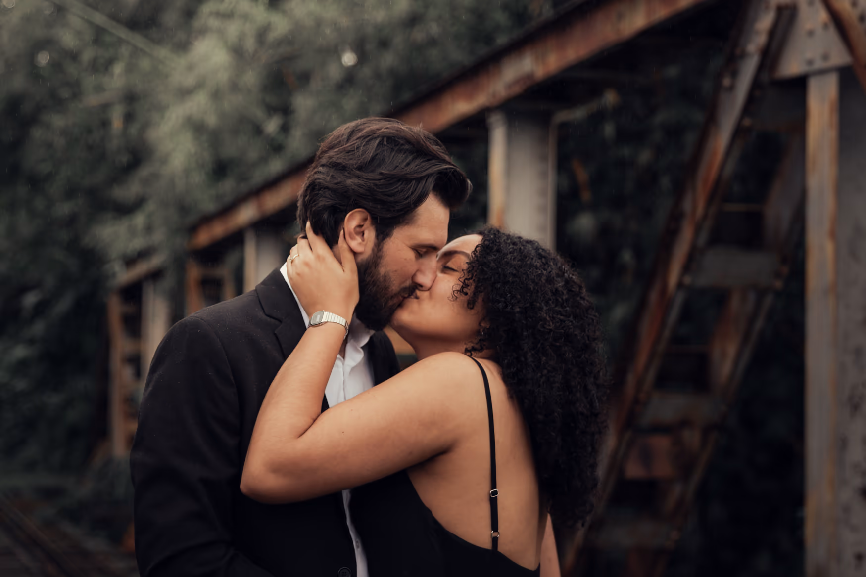 Casal se beijando em uma ponte de ferro enferrujada