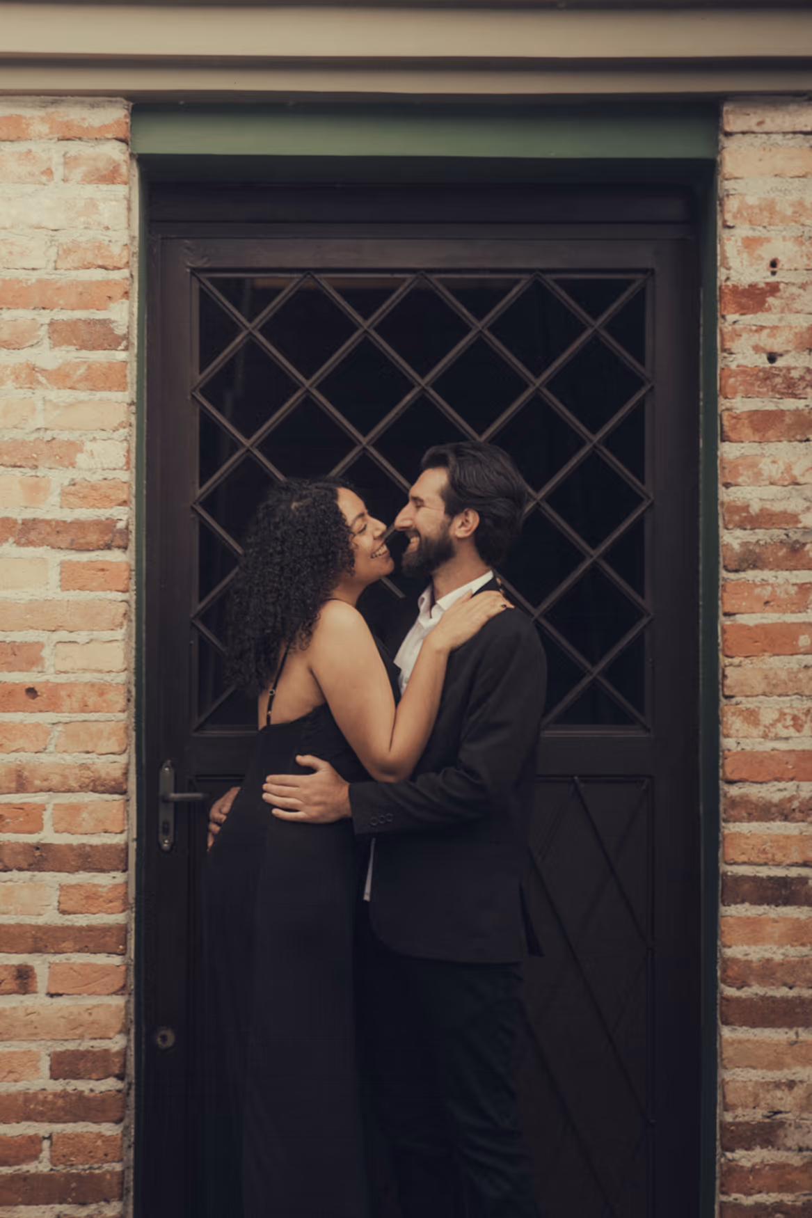 Casal se beijando em frente a uma porta com grade